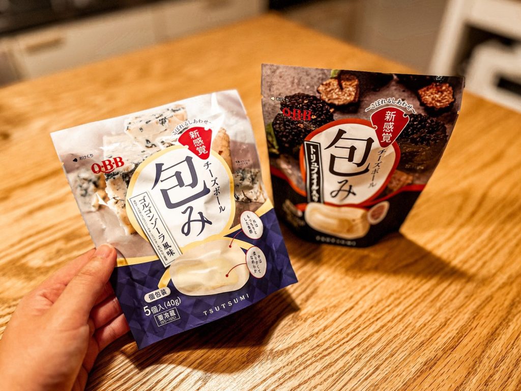 「QBB チーズボール包み」のゴルゴンゾーラ風味とトリュフオイル風味のパッケージがテーブルに置いてある。