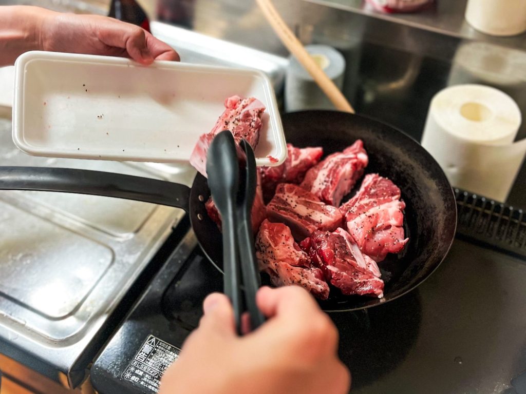 スペアリブをフライパンに投入している。
