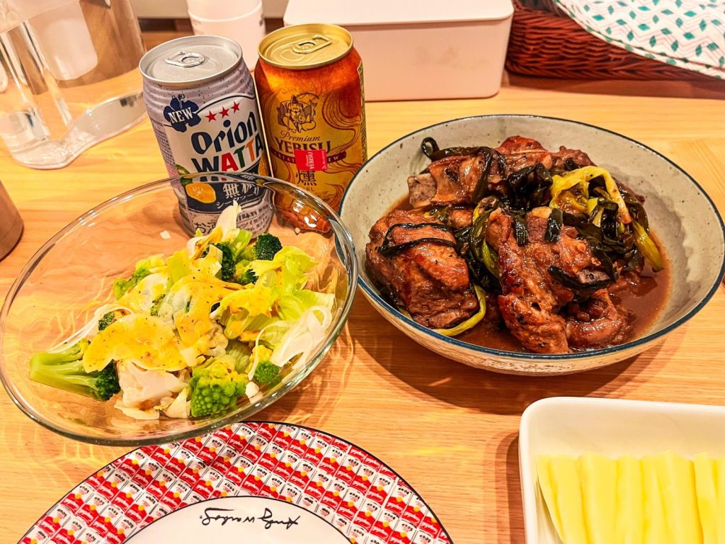 スペアリブの煮込み料理とサラダ、お酒などが並んだ食卓。