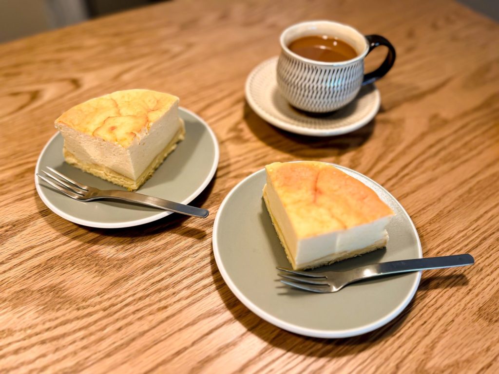 カットして小皿に移した豆腐のスフレチーズケーキが2つと、その奥にホットコーヒーが1つある。