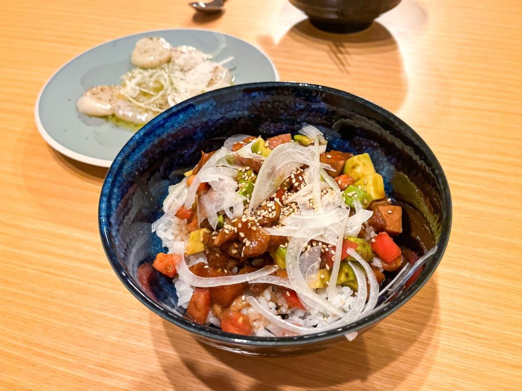 手前にサーモンのポキ丼、奥にホタテのカルパッチョが並んだ食卓。