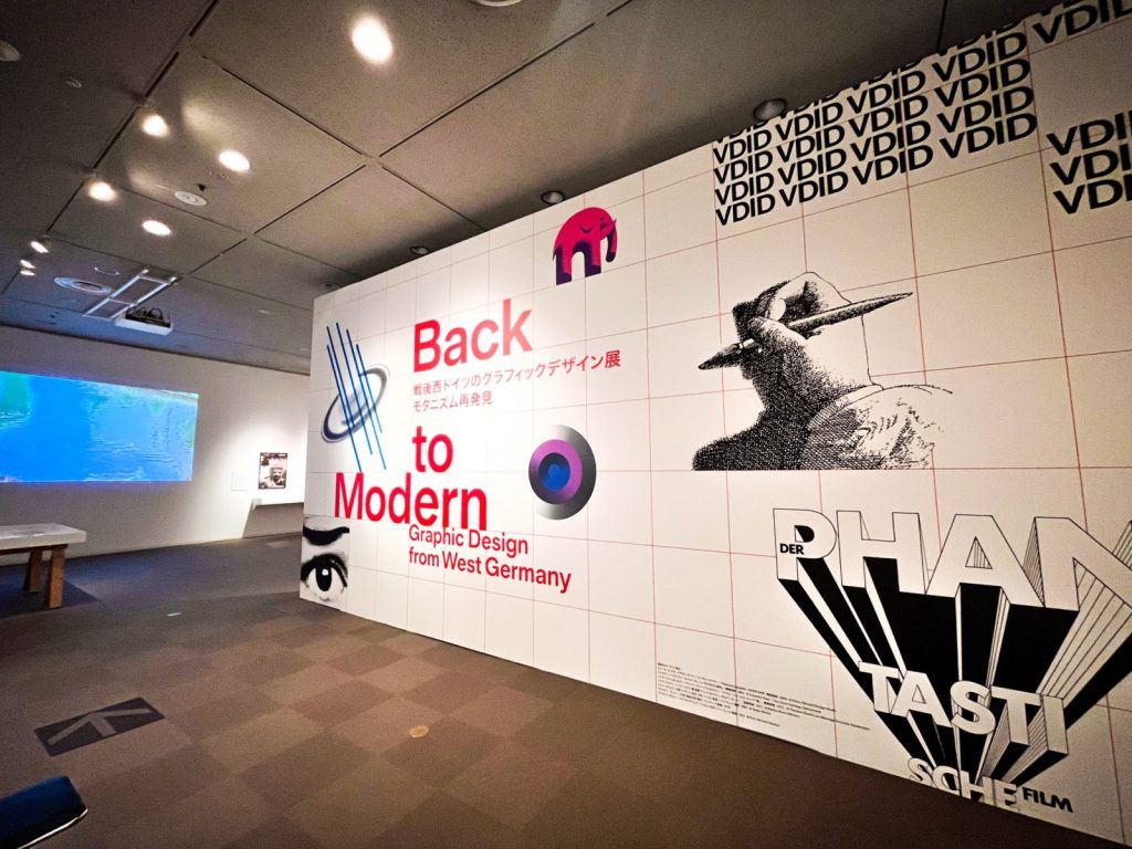 展覧会の入り口の様子。壁には展覧会のタイトルとキービジュアルが大きくプリントされている。